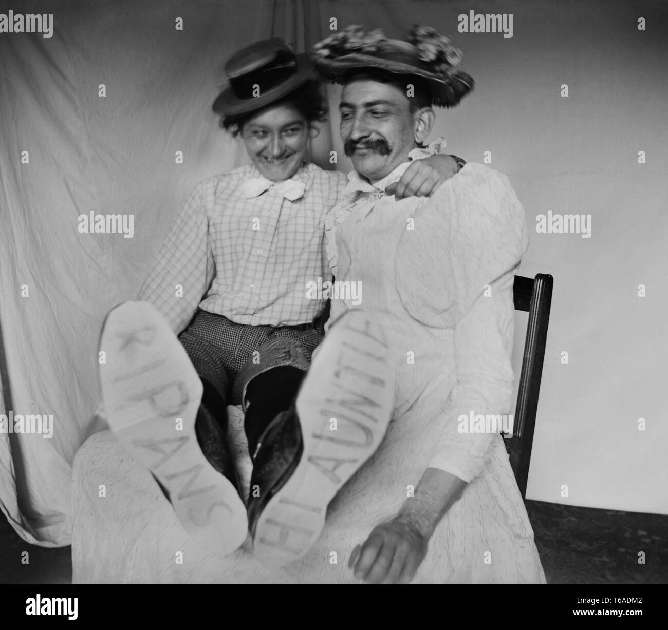 Un homme dans une robe et une femme en pantalon s'amusent ensemble, ca. 1910. Banque D'Images