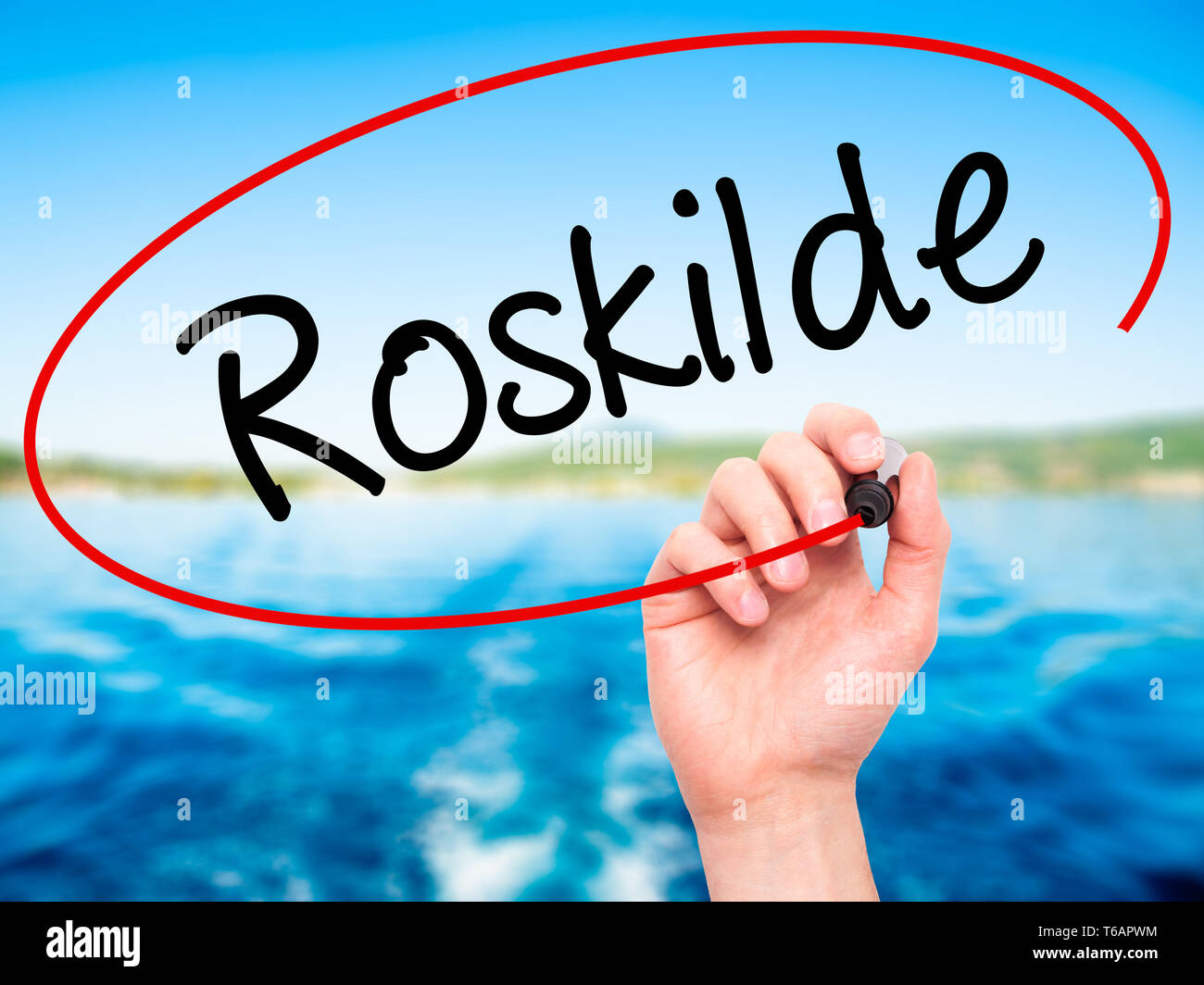 Man main écrit Roskilde avec marqueur noir sur l'écran visuel Banque D'Images