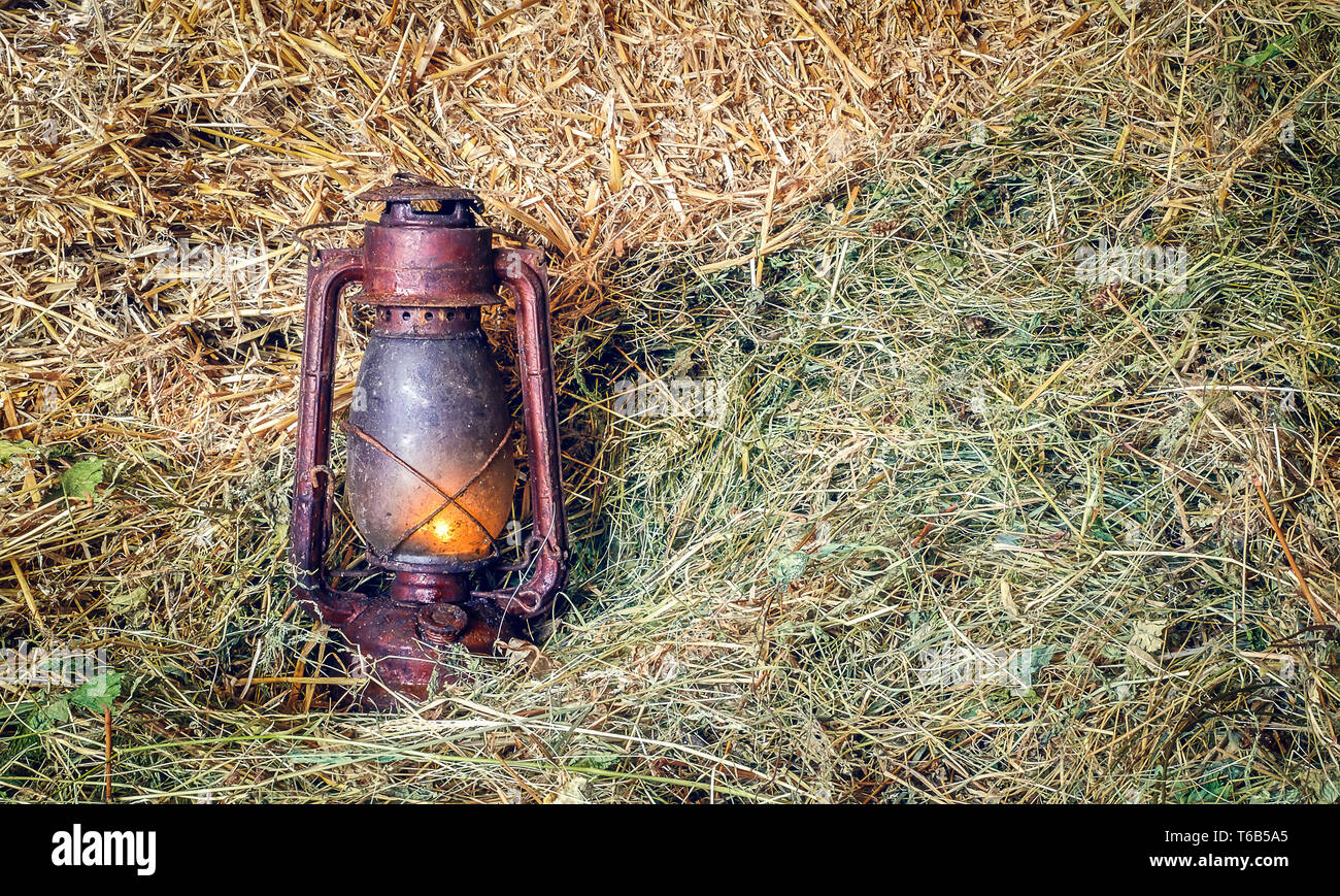 Vintage lampe lanterne à huile allumé sur la paille Banque D'Images