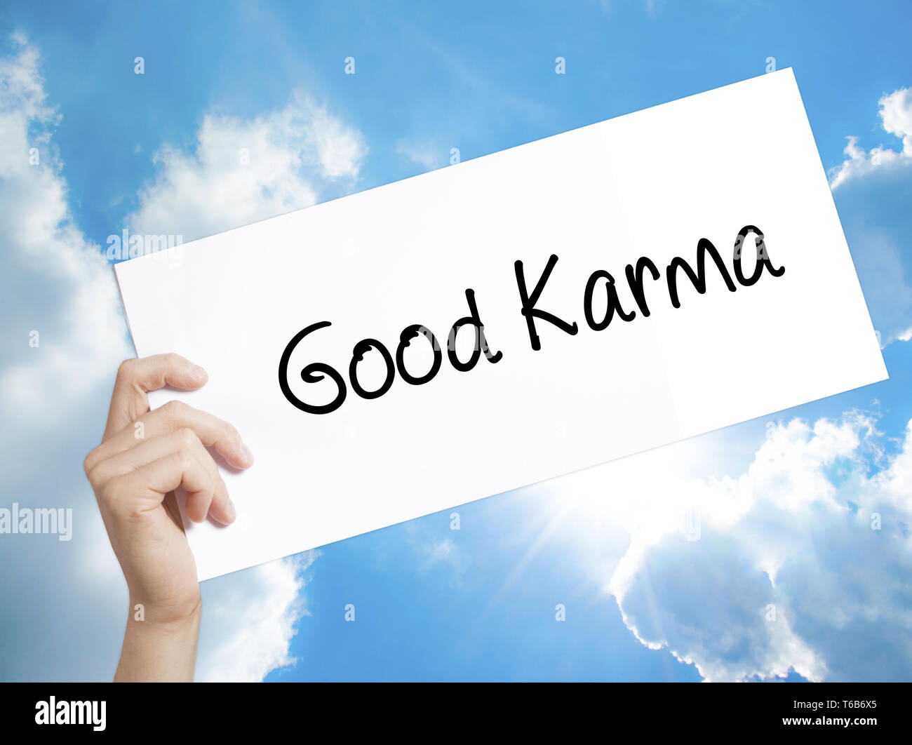 Bon Karma signer sur papier blanc. Tenir la main de l'homme papier avec texte. Isolé sur fond de ciel Banque D'Images
