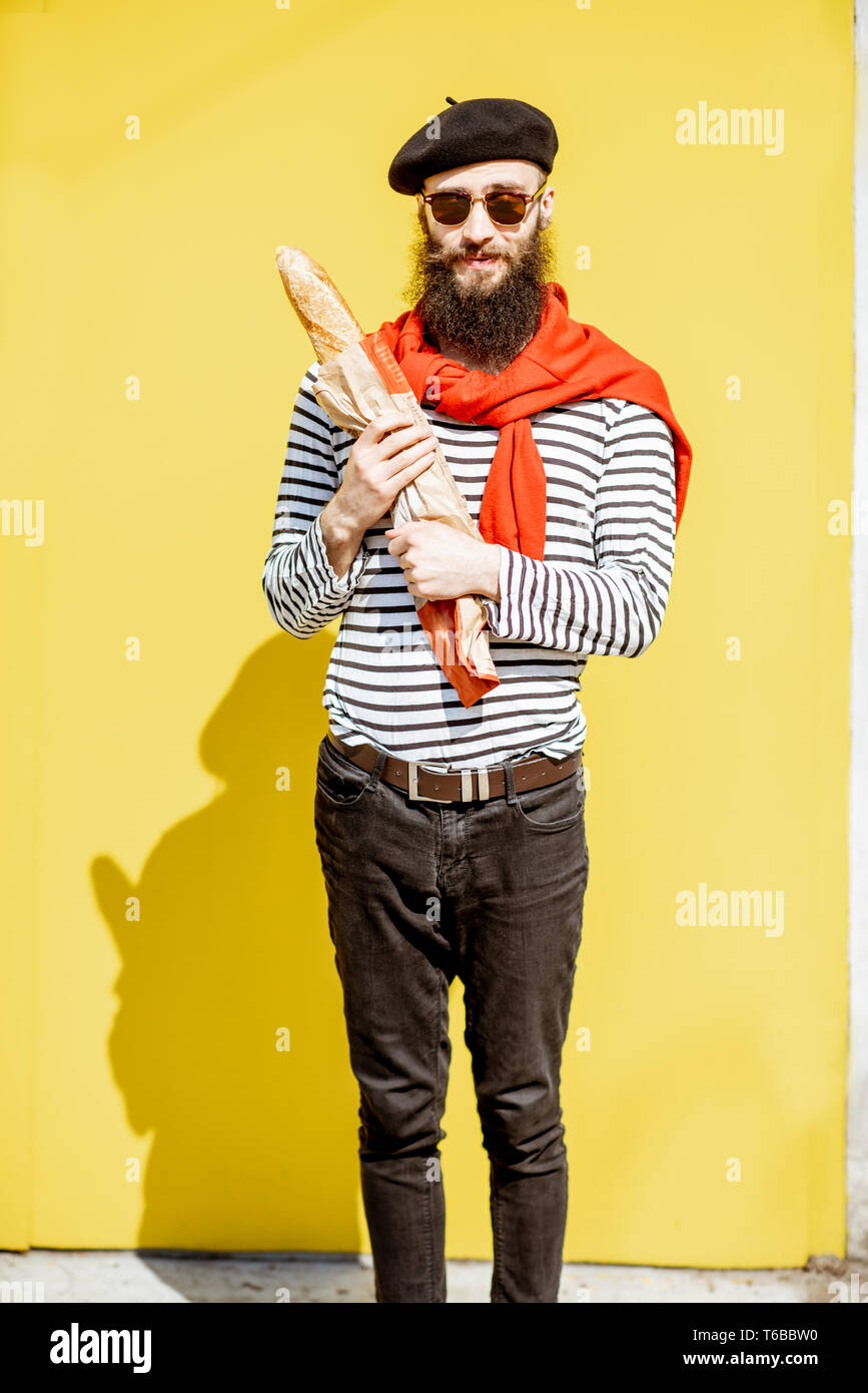 Portrait d'un homme habillé en élégant style français avec chemise rayée,  chapeau et foulard rouge sur le fond jaune Photo Stock - Alamy