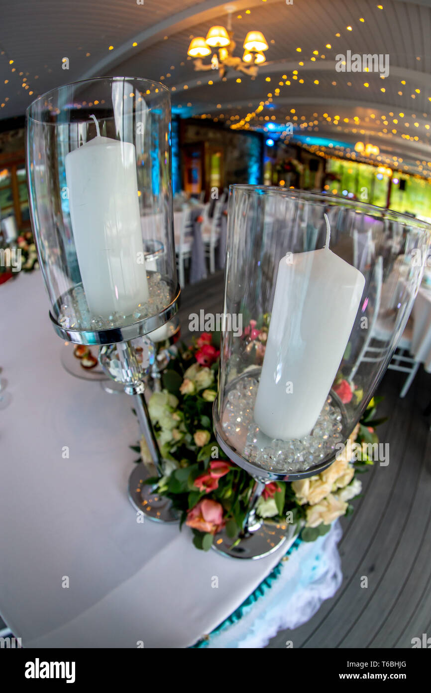 Décor de table pour réception de mariage. Chandelier avec des bougies et de bouquet de fleurs sur la table de mariage avec nappe blanche. Tourné avec des poissons Banque D'Images