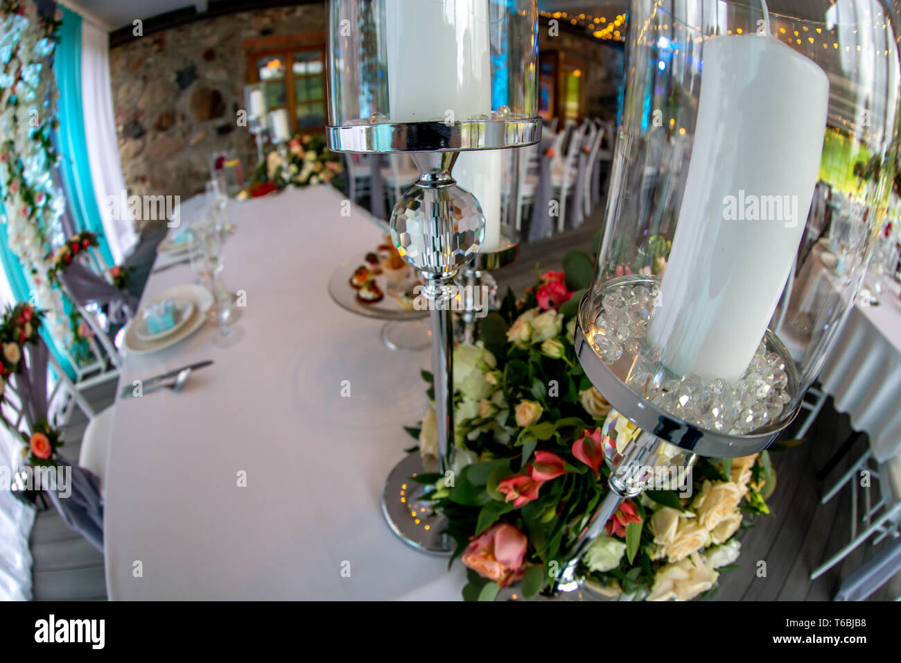 Décor de table pour réception de mariage. Chandelier avec des bougies et de bouquet de fleurs sur la table de mariage avec nappe blanche. Tourné avec des poissons Banque D'Images