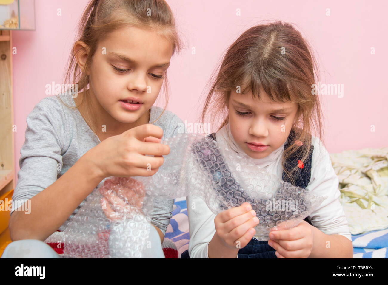 Deux jeunes filles bulles d'emballage gonflable captivé burst paquet Banque D'Images