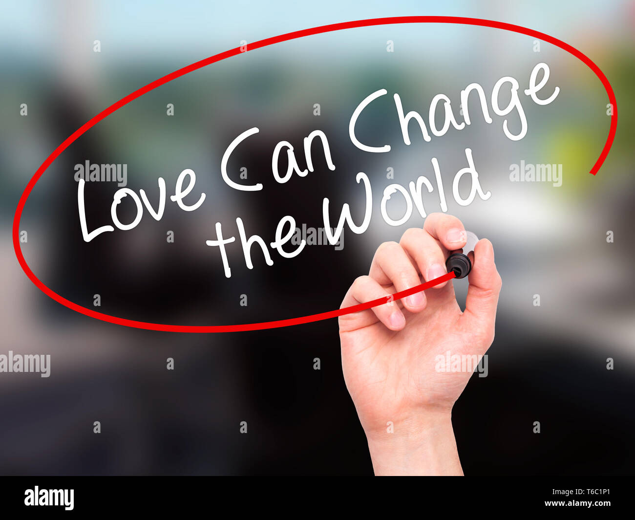 La main de l'homme écrit l'amour peut changer le monde avec marqueur noir sur l'écran visuel Banque D'Images