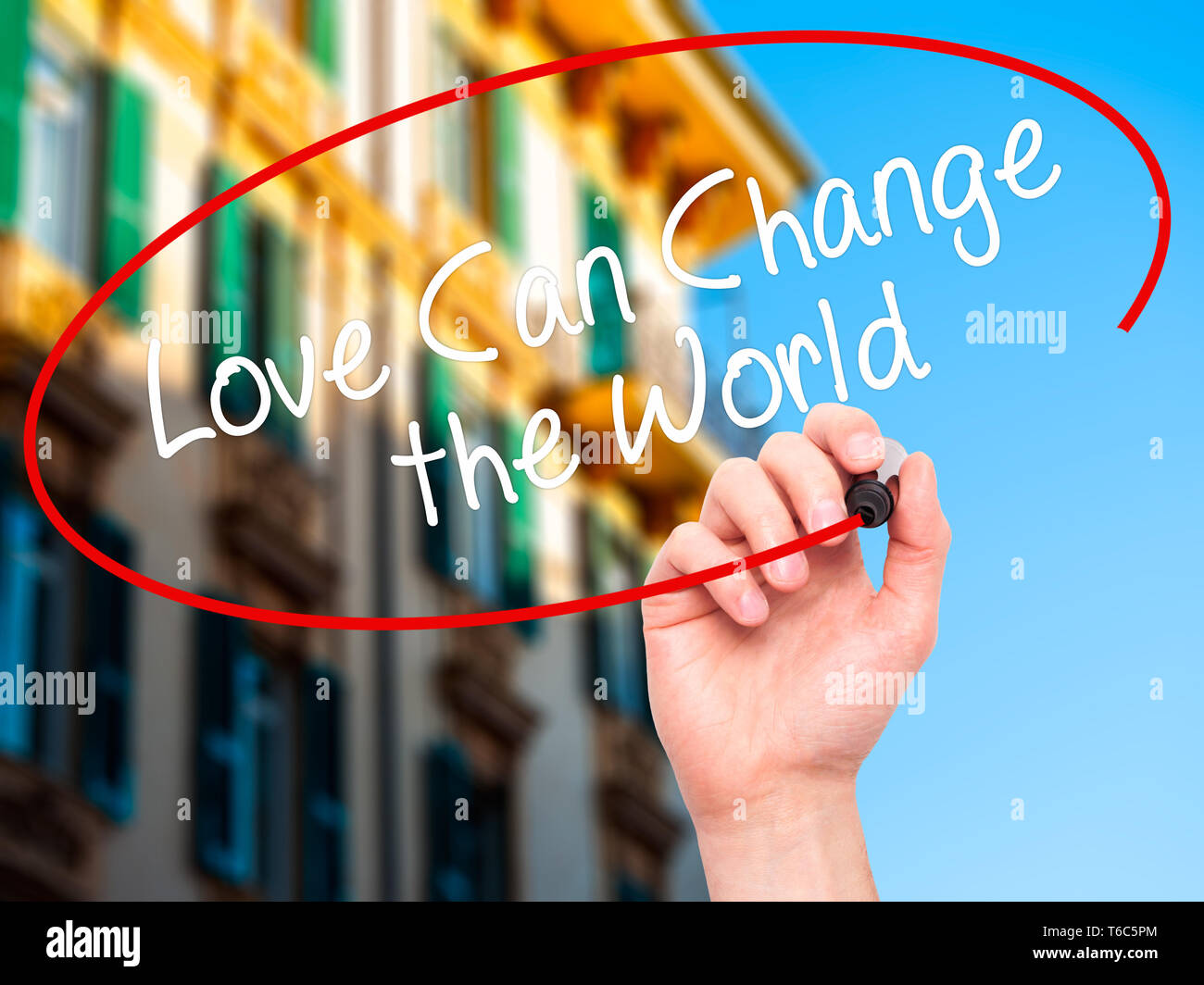 La main de l'homme écrit l'amour peut changer le monde avec marqueur noir sur l'écran visuel Banque D'Images