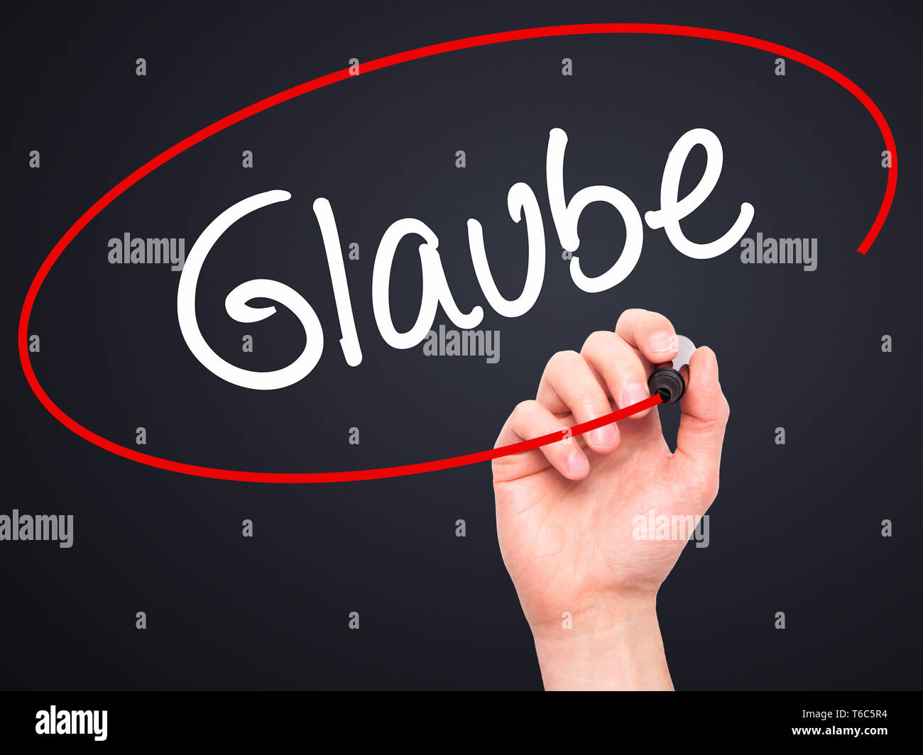Man main écrit Glaube (Croyez en allemand) avec marqueur noir sur l'écran visuel. Banque D'Images
