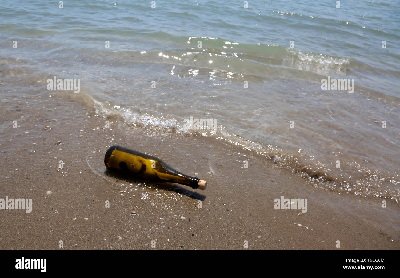 Le flacon en verre contenant un message porté par les vagues sur le sable de la rive Banque D'Images
