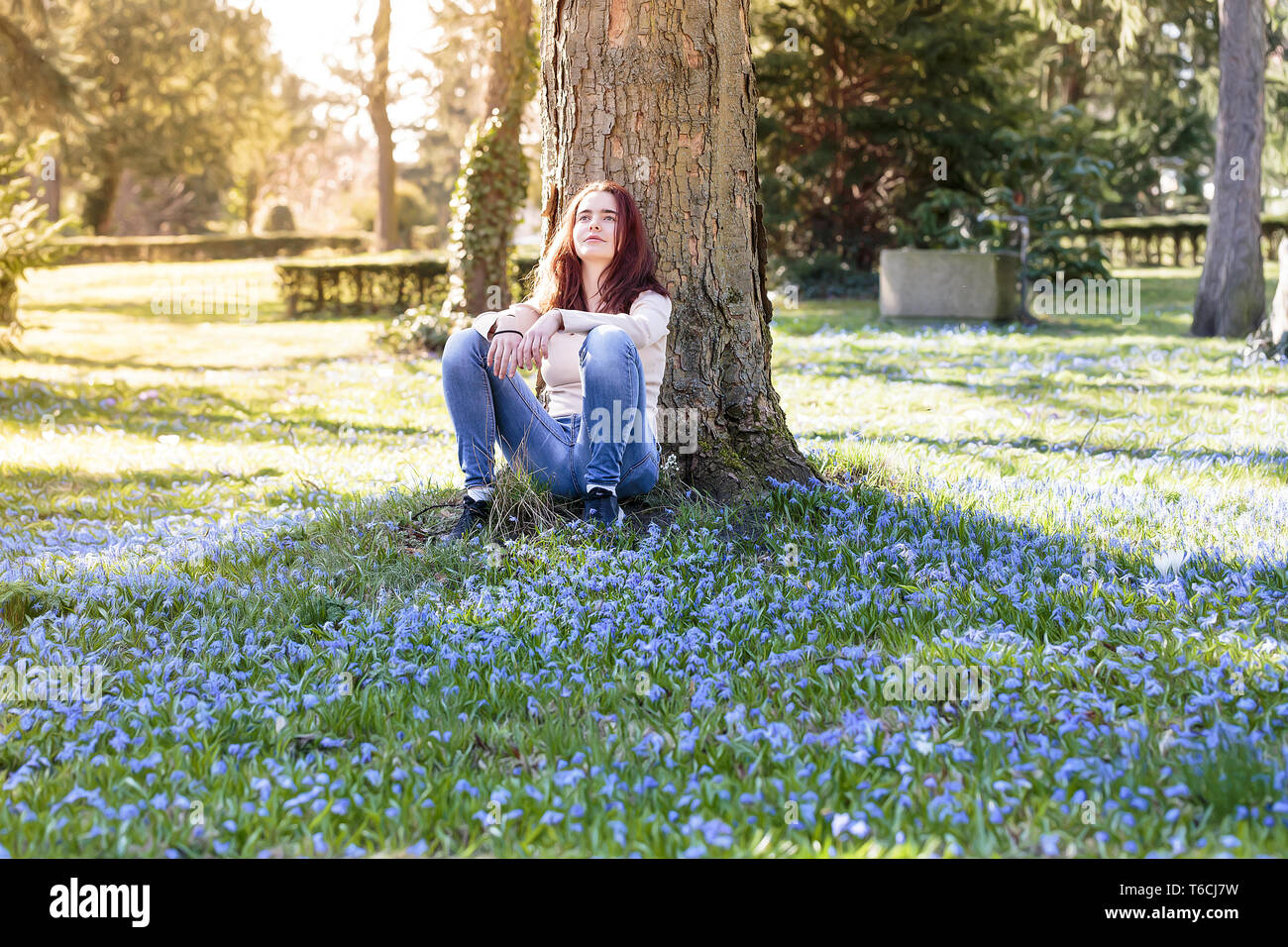 Young smiling woman sitting on a spring flower meadow Banque D'Images
