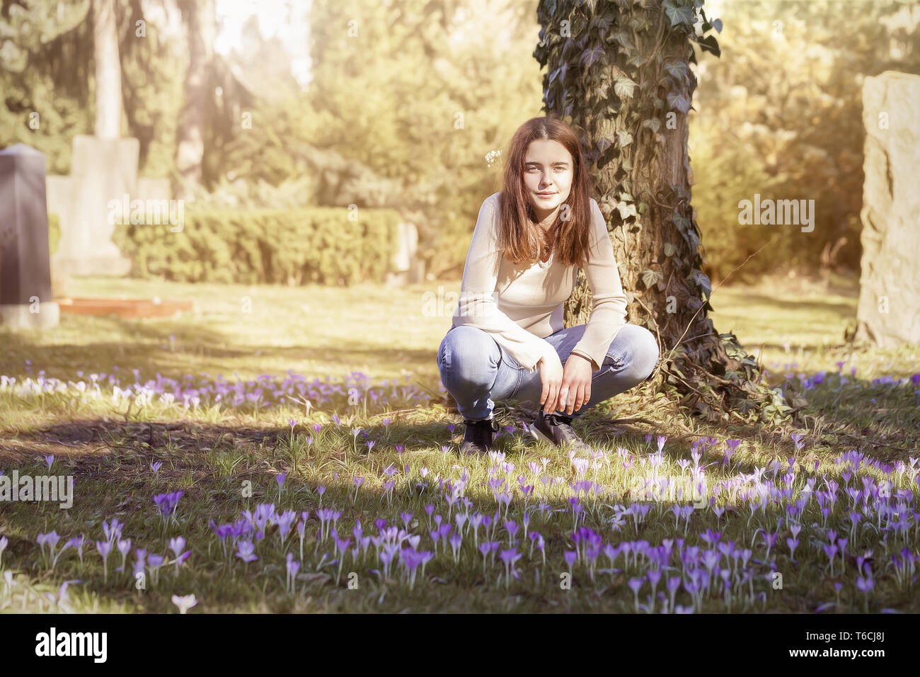 Jeune femme accroupi sur une prairie de fleurs de printemps Banque D'Images