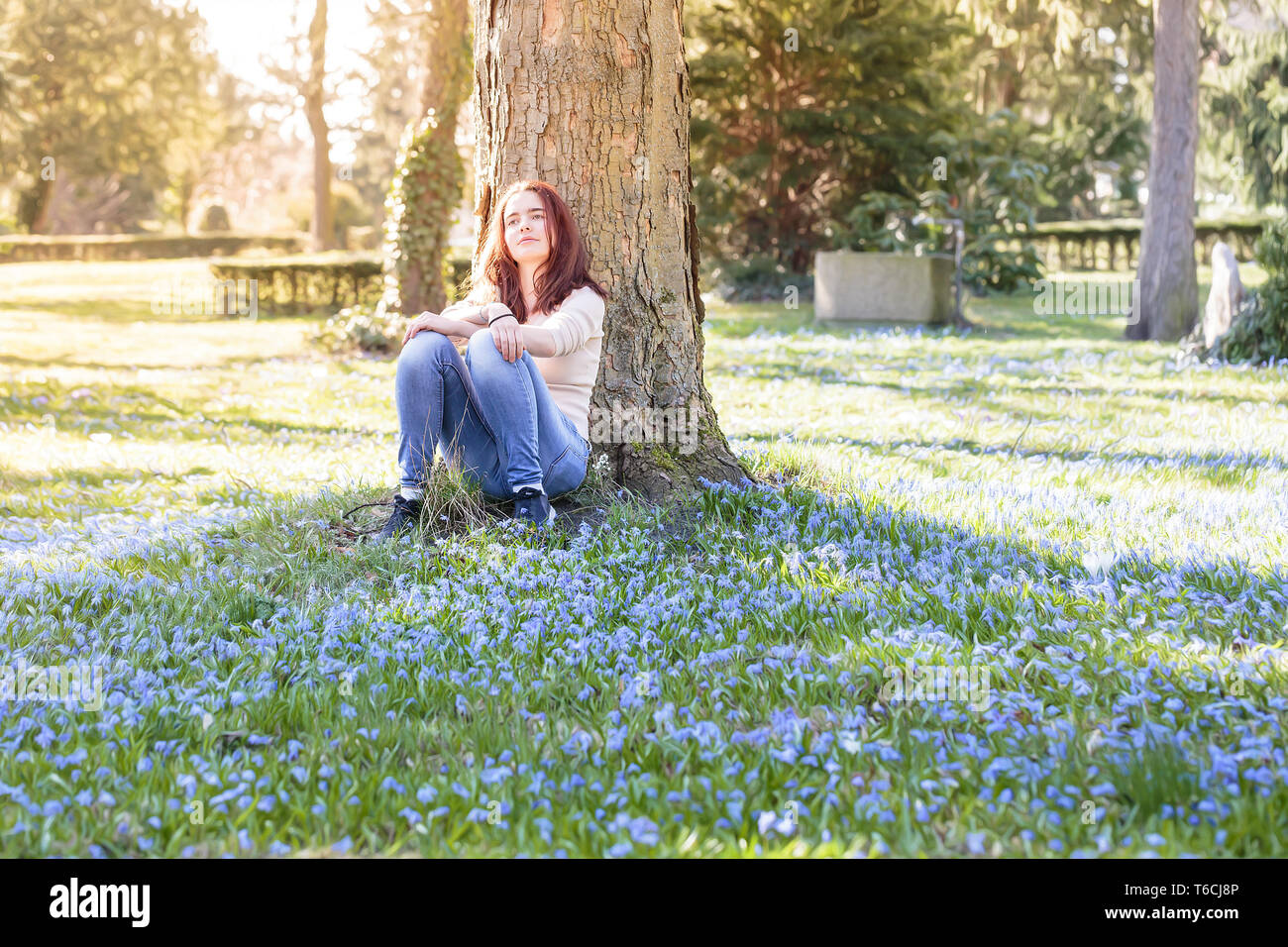 Young smiling woman sitting on a spring flower meadow Banque D'Images