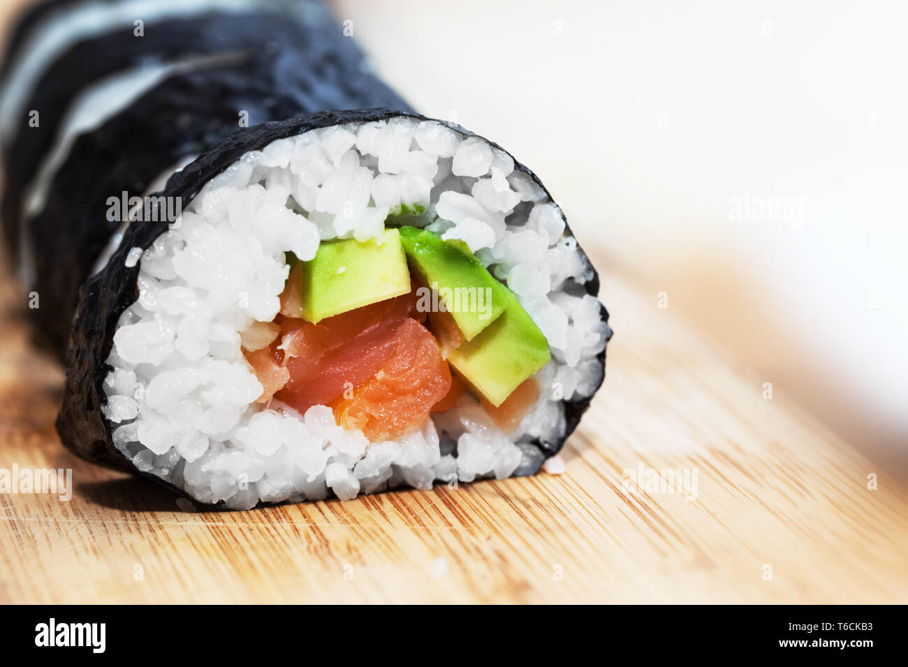 Des sushis au saumon, avocat, riz aux algues et baguettes sur la table en bois Banque D'Images