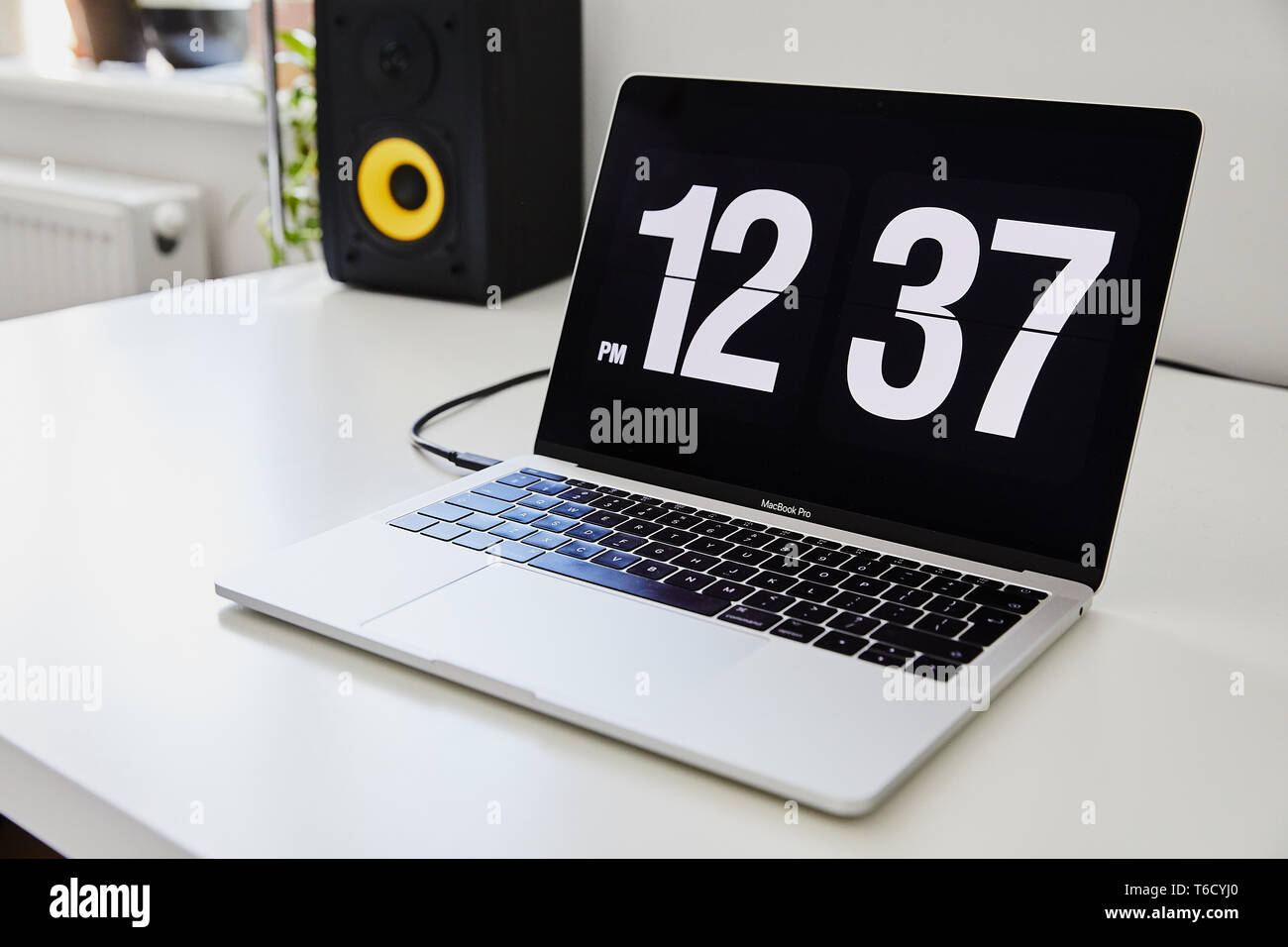 Apple MacBook Pro ordinateur portable avec l'écran de veille horloge sur le  grand bureau bureau Ikea blanc avec le jaune, noir haut-parleurs de  l'iPhone à l'arrière-plan Photo Stock - Alamy