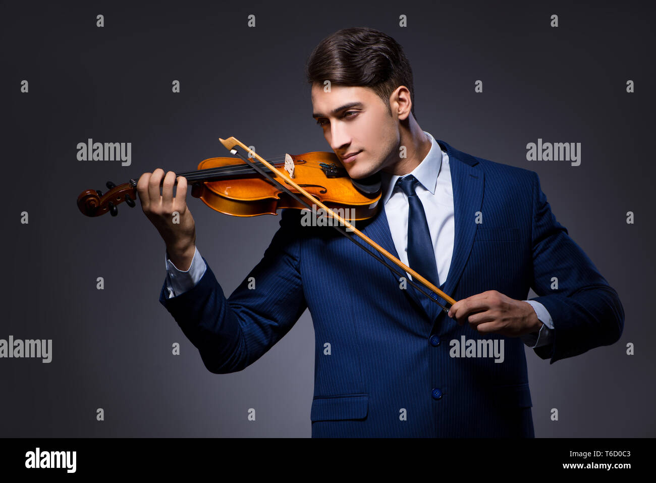 Young man playing violin in dark room Banque D'Images