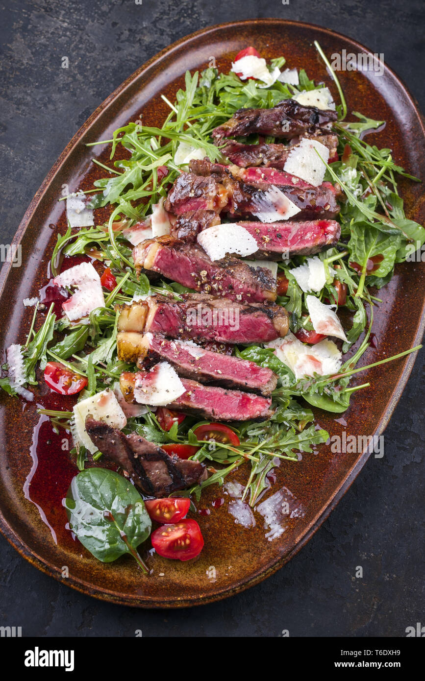 Italien traditionnel steak tagliata de parmesan et salade comme close-up sur une plaque Banque D'Images