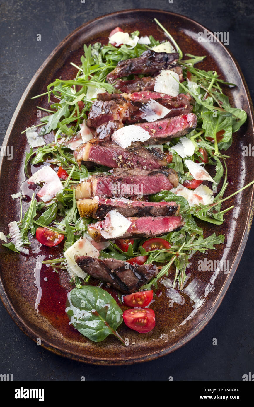 Italien traditionnel steak tagliata de parmesan et salade comme close-up sur une plaque Banque D'Images