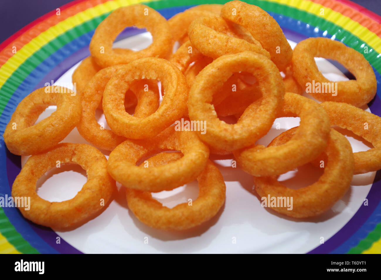 Anneau oignon chips sur une assiette en papier arc-en-ciel Banque D'Images