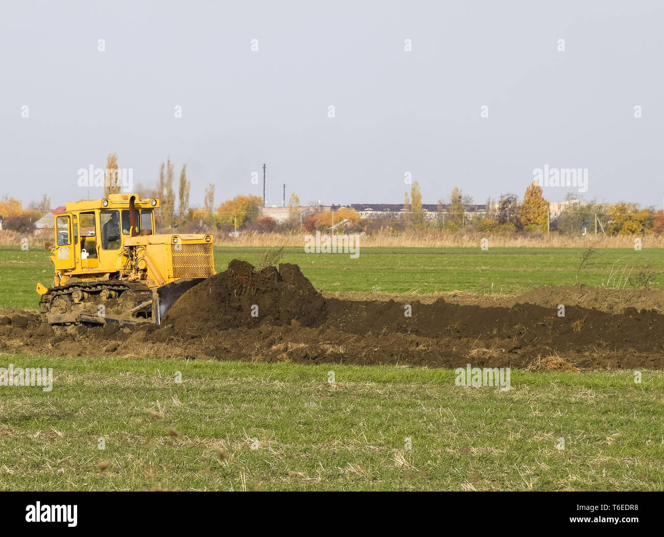 Le tracteur jaune avec grederom terre rend la mise à niveau. Banque D'Images