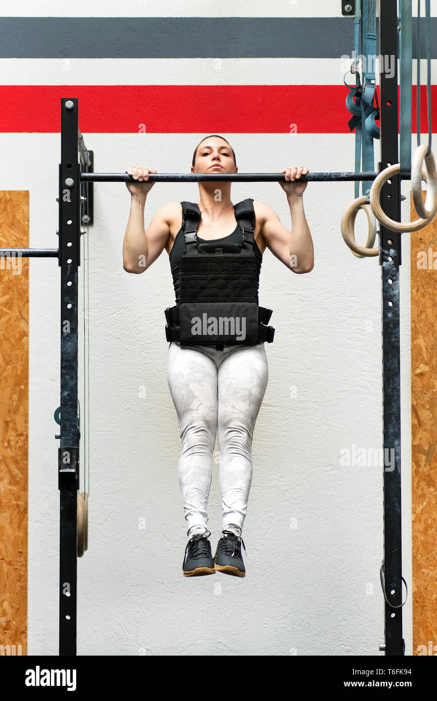 Jeune femme faisant de l'athlète-pondéré sur un bar portant une veste lourde pour renforcer les muscles de son corps dans un concept de santé et de remise en forme Banque D'Images