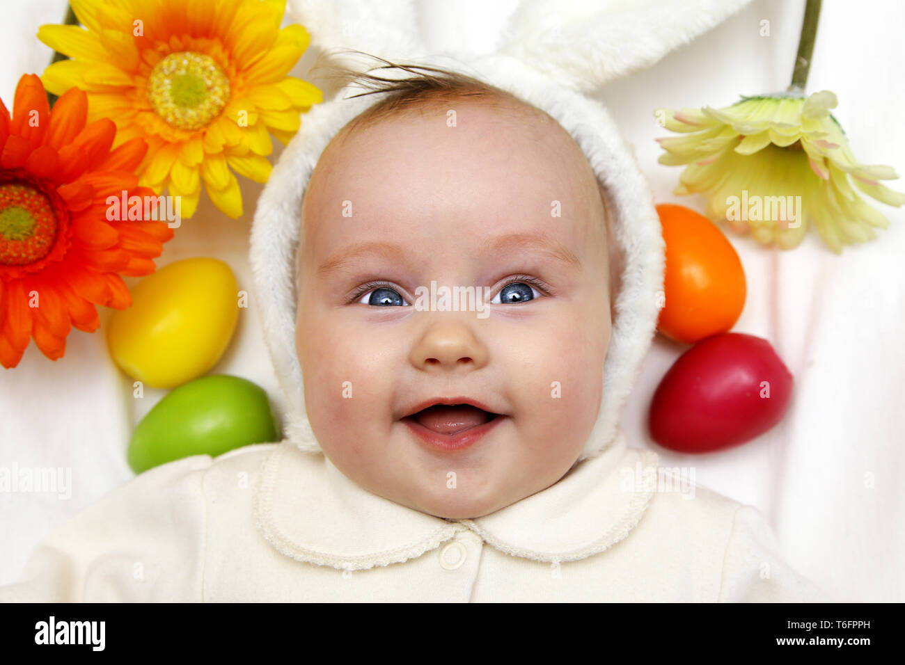Nouveau-né fille garçon bébé européen avec les oreilles de lapin de Pâques 3 mois parmi les oeufs colorés et des fleurs Banque D'Images