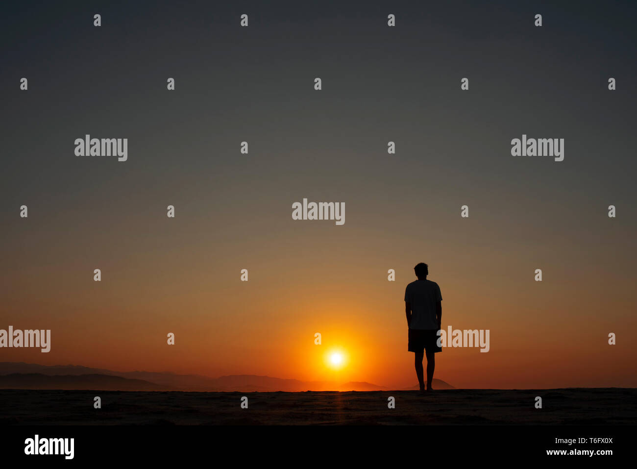 Silhouette d'homme qui regarde le beau soleil orange allumé sur l'horizon. Coastal lever/coucher du concept. Chacahua, Oaxaca, Mexique. Apr 2019 Banque D'Images