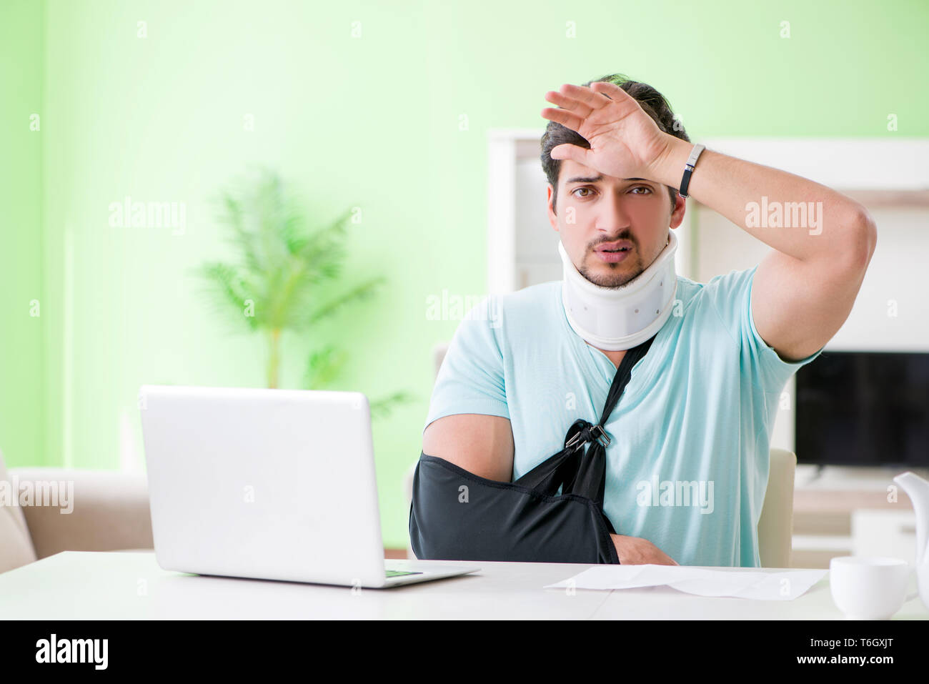 Jeune homme étudiant avec cou et blessures de la main à la maison Banque D'Images