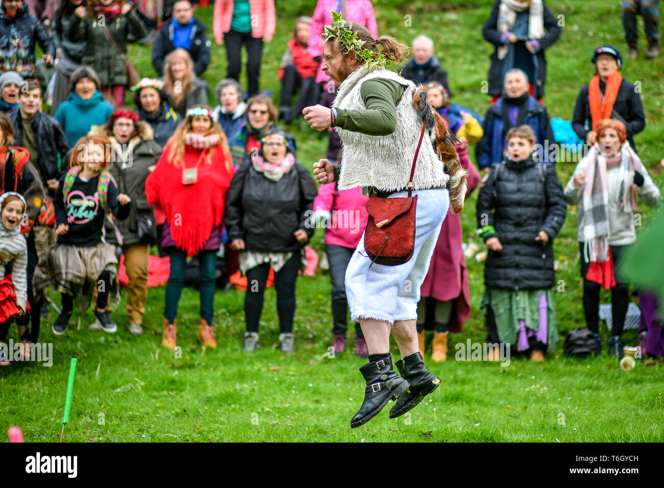 Un homme passe dans l'air alors que la foule libère de l'énergie vocale pendant la célébration Beltane à Glastonbury Chalice Well, où les gens se rassemblent pour observer une interprétation moderne de l'antique fertilité païenne celtique sacre du printemps. Banque D'Images