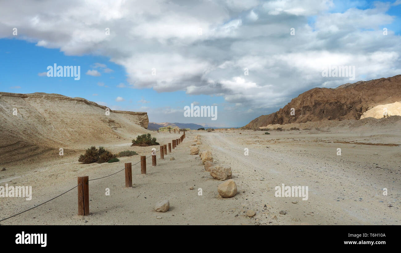 De gros nuages blancs et chemin de sable dans la région de la Mer Morte. Banque D'Images