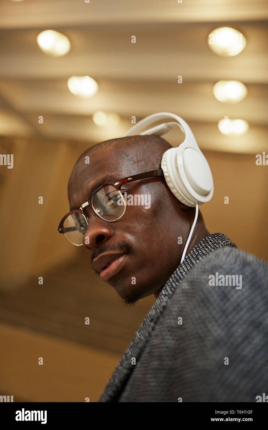 Head and shoulders portrait of handsome African man wearing headphones looking at camera tout en écoutant de la musique Banque D'Images