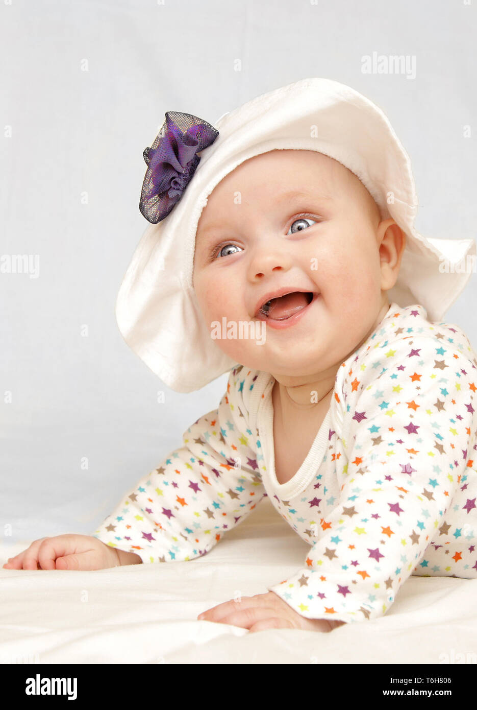 L'nouveau-né baby girl smiling portant chapeau d'été avec fleur bleue 6 mois Banque D'Images