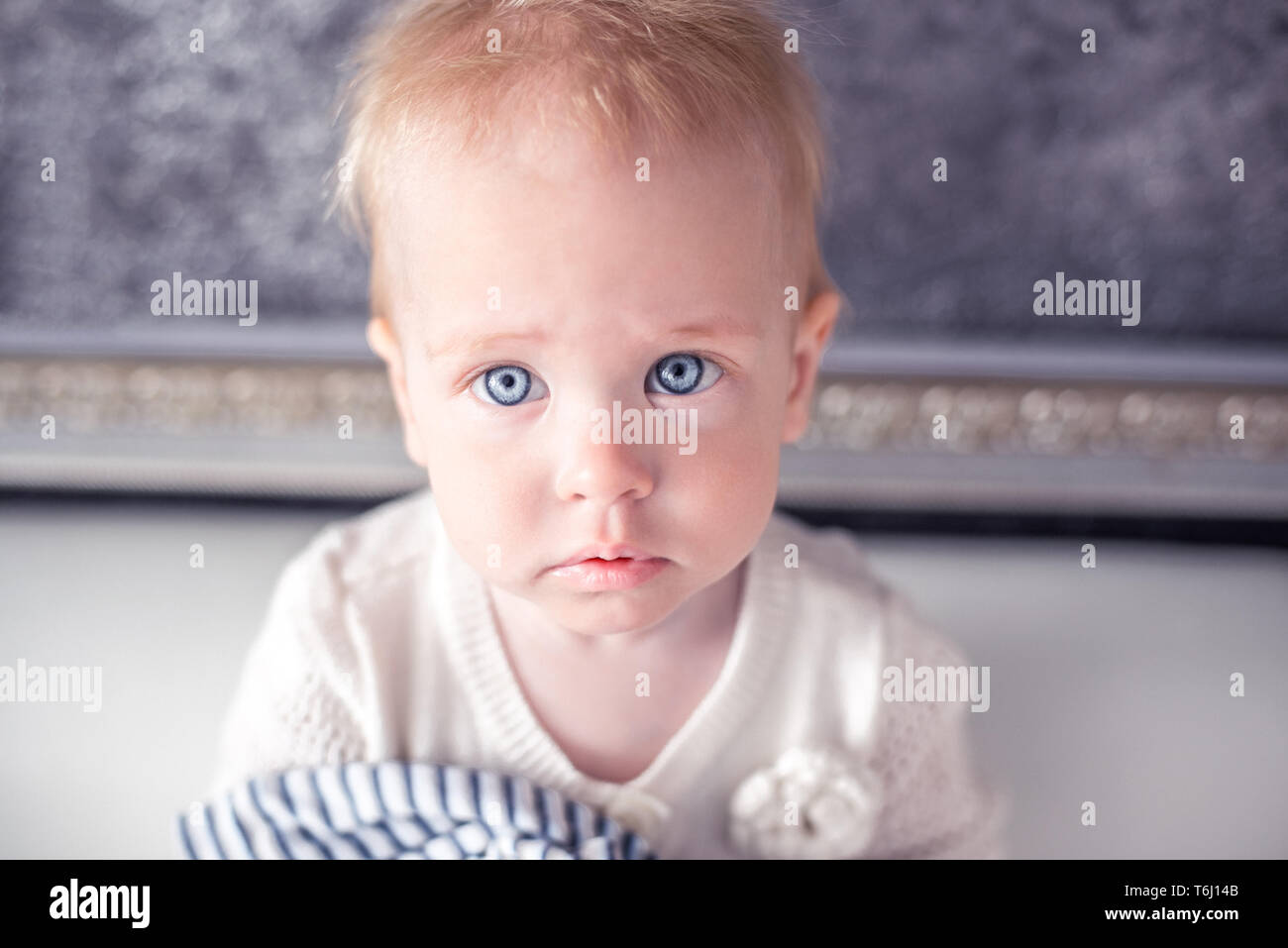 Un adorable petit bébé avec les cheveux blonds et les yeux bleus d'un Banque D'Images