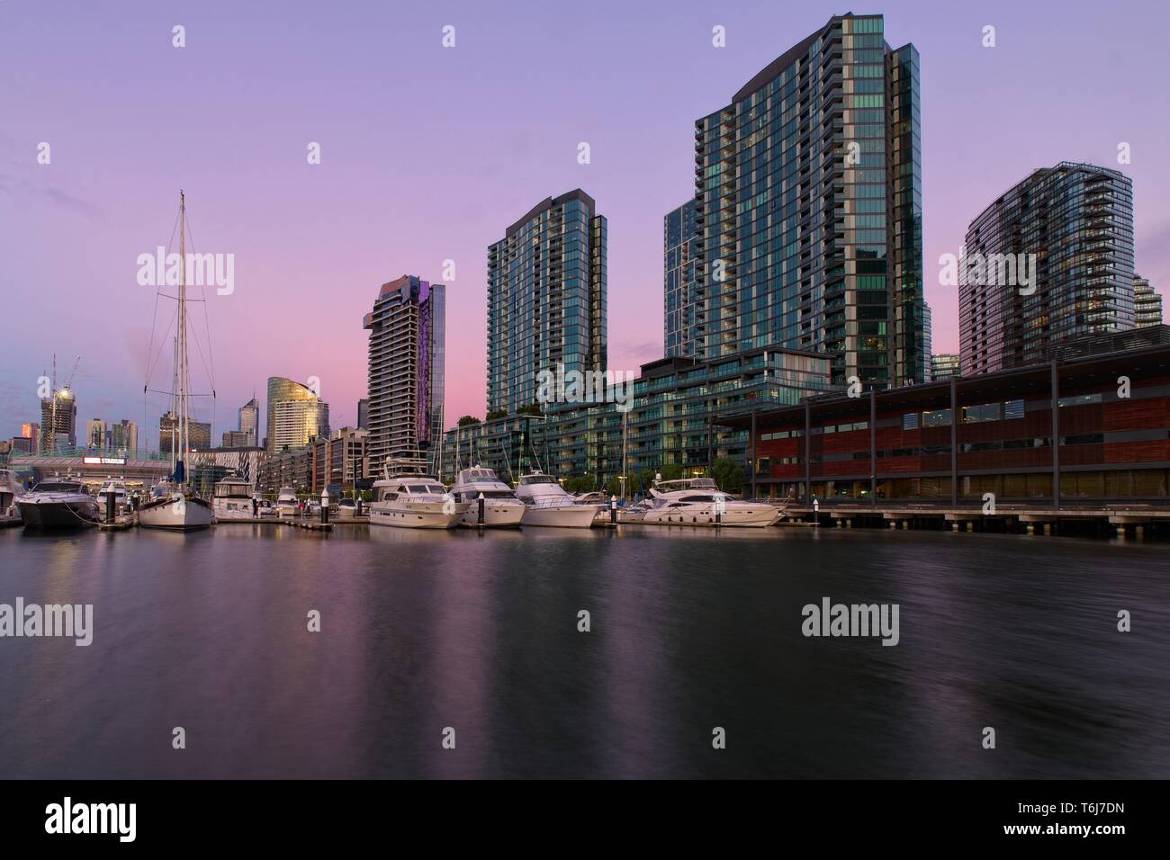 Docklands Melbourne Victoria Promenade du port de plaisance et de grands immeubles à appartements de la tons roses et mauves de coucher du soleil Banque D'Images