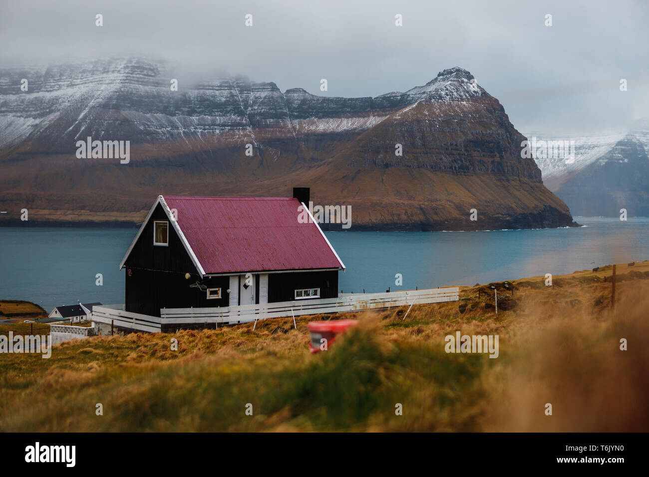 Féroïen typique maison en bois noir avec toit coloré dans le village Viðareiði avec neiges de Kunoy et Kalsoy island (îles Féroé) Banque D'Images