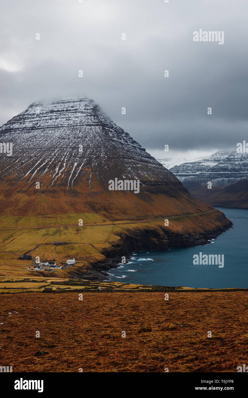 Vue de la Kap Enniberg vers le petit village, Viðareiði Viðareiði kirkja, son fjord et montagnes neige-couvertes (îles Féroé, Danemark, Europe) Banque D'Images