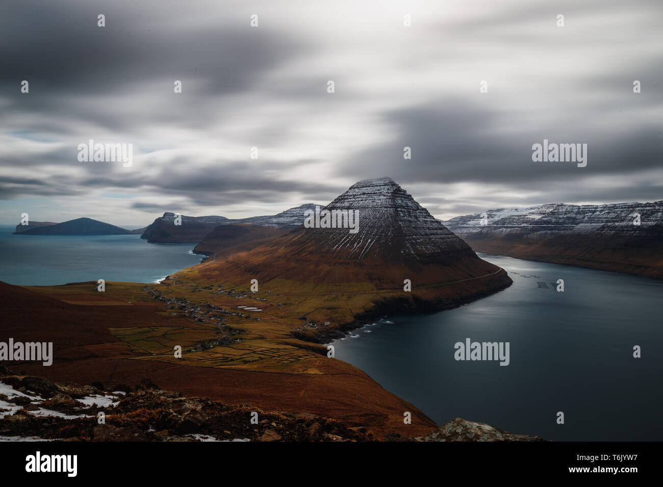 L'exposition longue vue panoramique à partir de la Kap Enniberg vers le village Viðareiði, son fjord avec des montagnes neige-couvertes (îles Féroé, Danemark, Europe) Banque D'Images