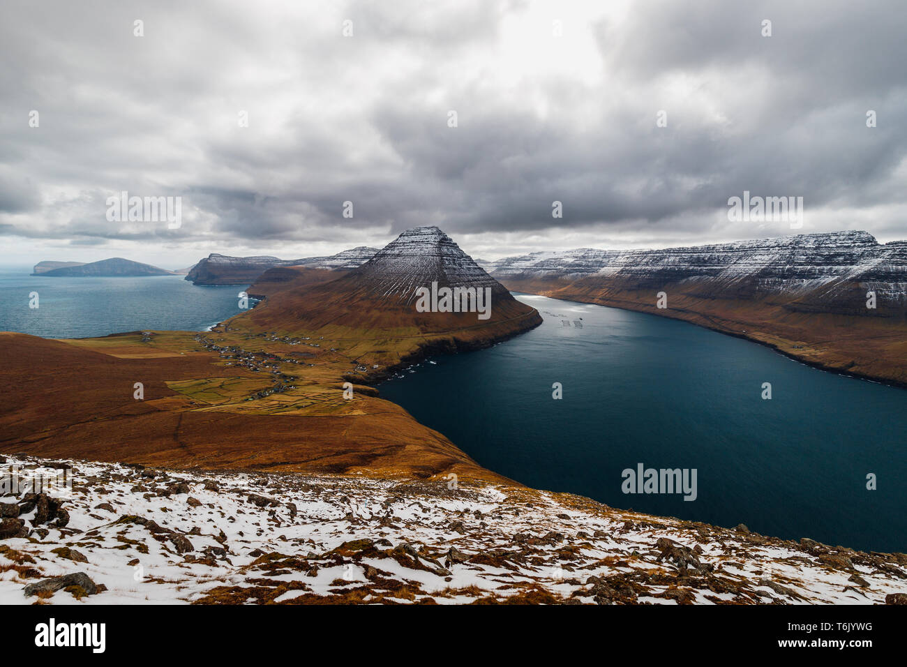 Vue d'un chemin de randonnée de la Kap Enniberg vers le petit village Viðareiði et son fjord avec des montagnes neige-couvertes (îles Féroé, Danemark, Europe) Banque D'Images