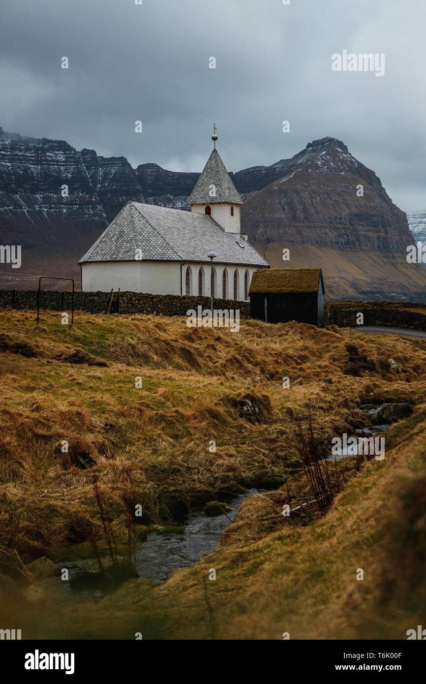 Vue sur l'église de Viðareiði Viðareiði Kirkja () avec moody ciel nuageux, brouillard et montagnes neige-couvertes (îles Féroé, Danemark, Europe) Banque D'Images