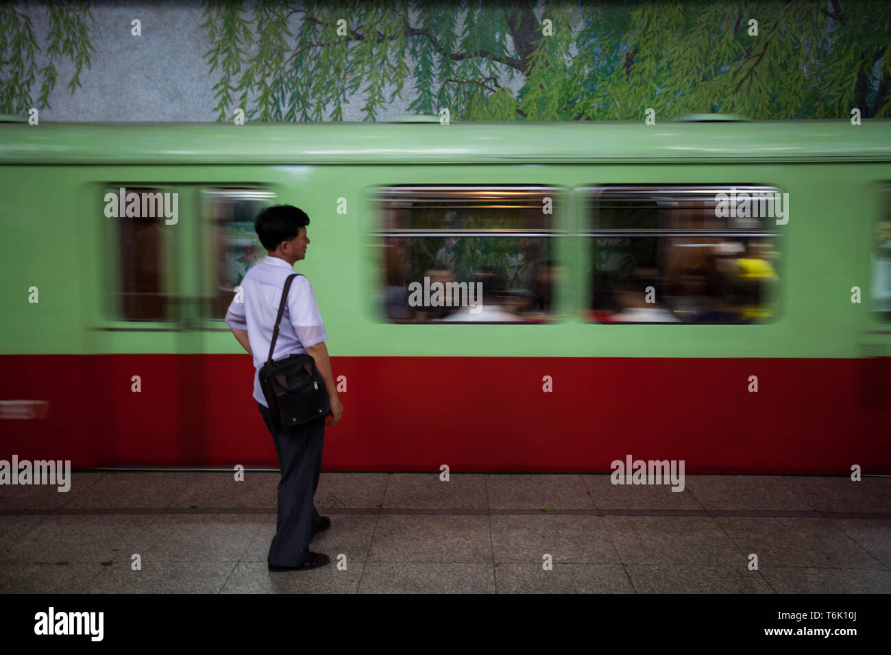 Un passager du métro de Pyongyang se dresse sur la plate-forme comme un train arrive. Banque D'Images