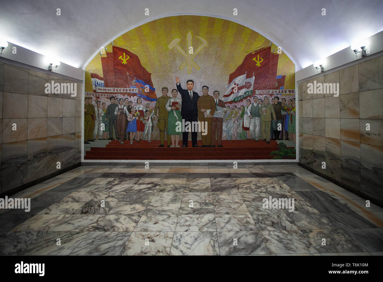 Une grande mosaïque murale intérieur d'une station de métro de Pyongyang montre drapeaux et les travailleurs et le symbole de la Corée du Nord Parti Communiste. Banque D'Images