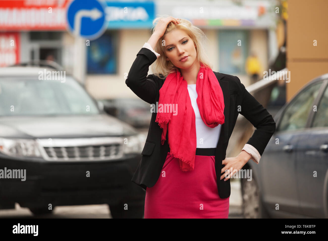 Mode jeune business woman walking in city street modèle féminin élégant vêtu de noir veste de costume et une écharpe rouge Banque D'Images