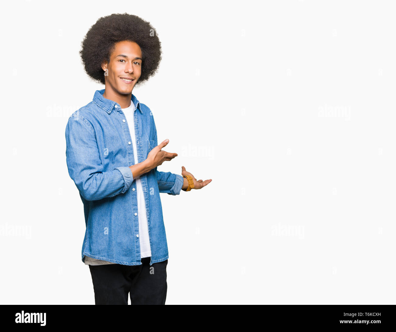 Young african american man with afro hair invitant à entrer smiling natural avec main ouverte Banque D'Images