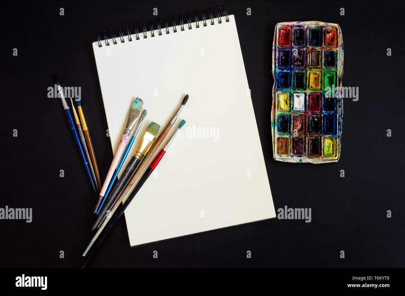 Artiste Créateur de travail télévision lay, immersive. Vue de dessus sur table avec carnet vierge, pinceaux et palettes de colorant. L'Art, atelier, peinture, dessin, Banque D'Images