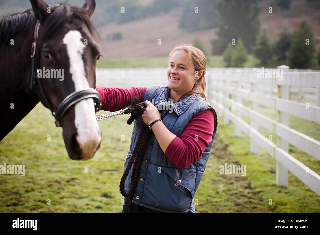Jeune femme debout dans un enclos avec son cheval. Banque D'Images