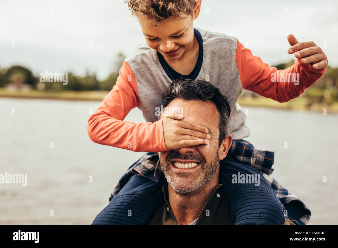 Père et fils s'amusant de passer du temps ensemble jouent à l'extérieur. Garçon fermant les yeux de son père assis sur ses épaules. Banque D'Images