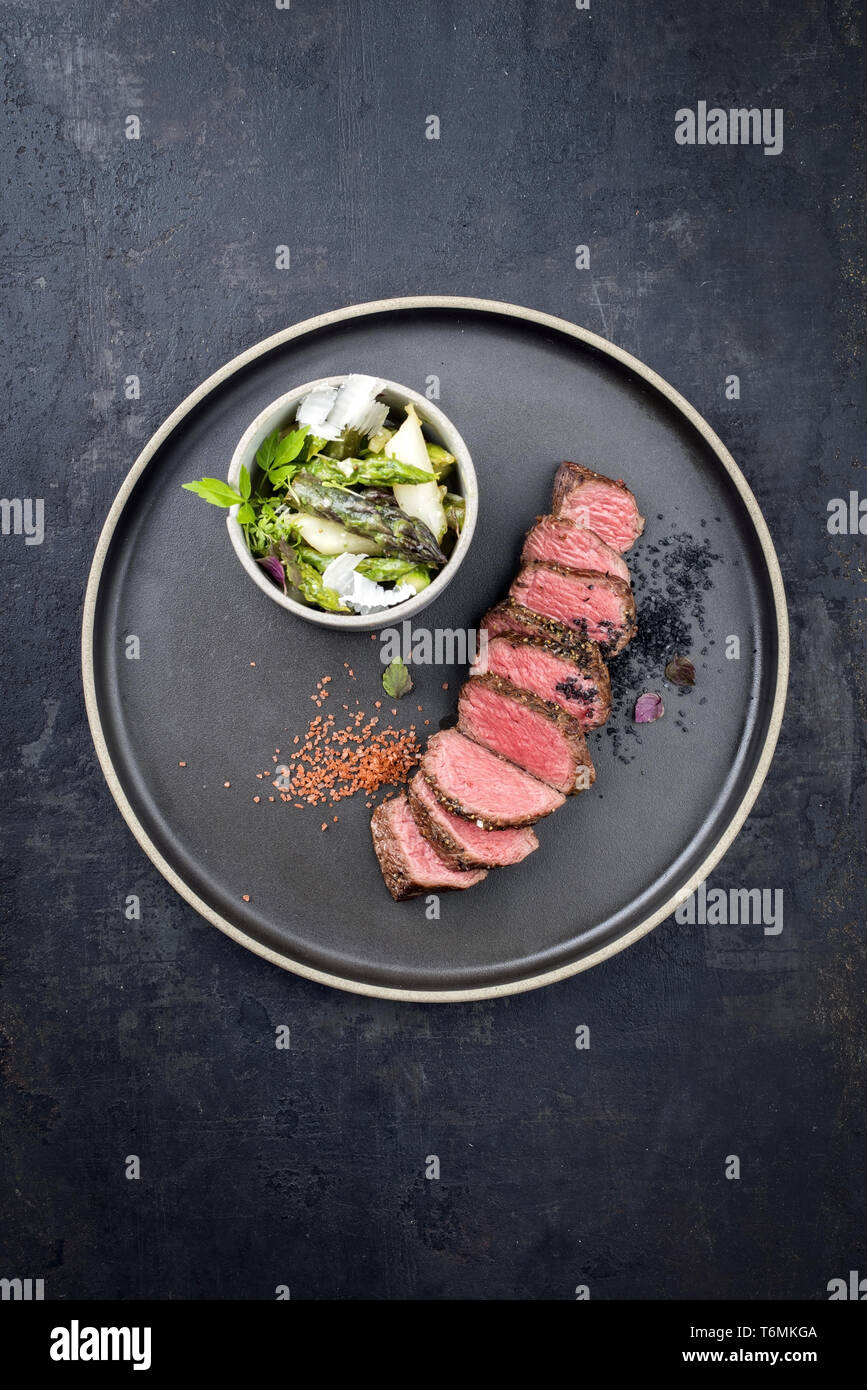 Barbecue en tranches d'âge moderne sec steak salade de printemps et d'asperges vertes et blanches comme libre sur une plaque avec spa de copie Banque D'Images