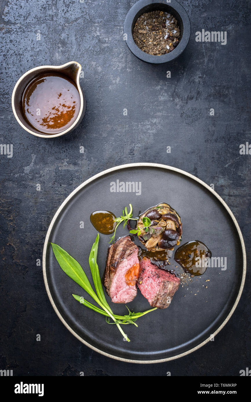 Barbecue traditionnel italien de tranches de steak à l'ail sauvage et pioppinos comme vue de dessus sur une plaque avec copie espace Banque D'Images