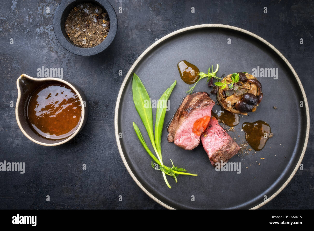 Barbecue traditionnel italien de tranches de steak à l'ail sauvage et pioppinos comme vue de dessus sur une plaque avec copie espace Banque D'Images