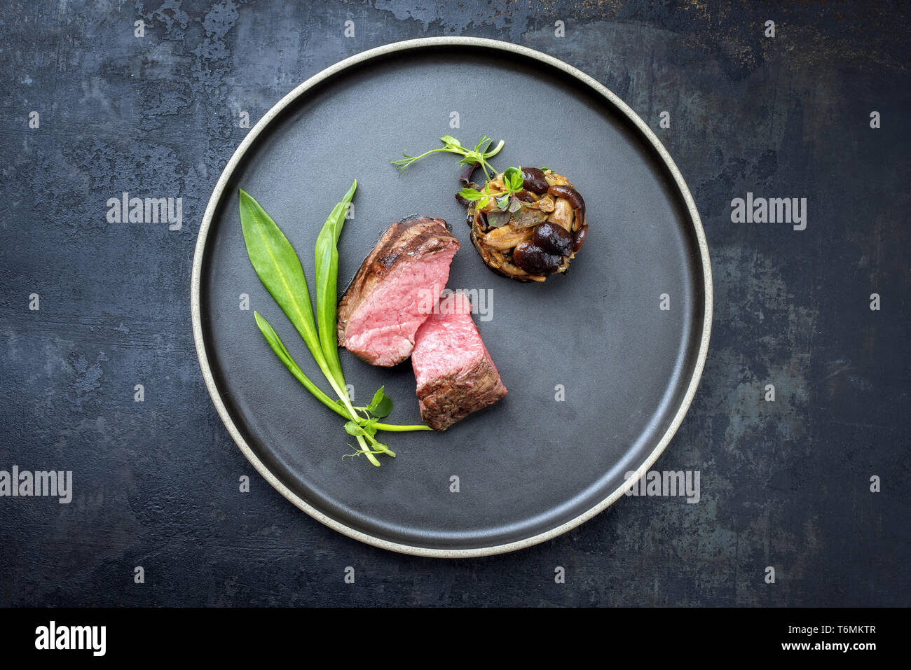 Barbecue traditionnel italien de tranches de steak à l'ail sauvage et pioppinos comme vue de dessus sur une plaque avec copie espace Banque D'Images