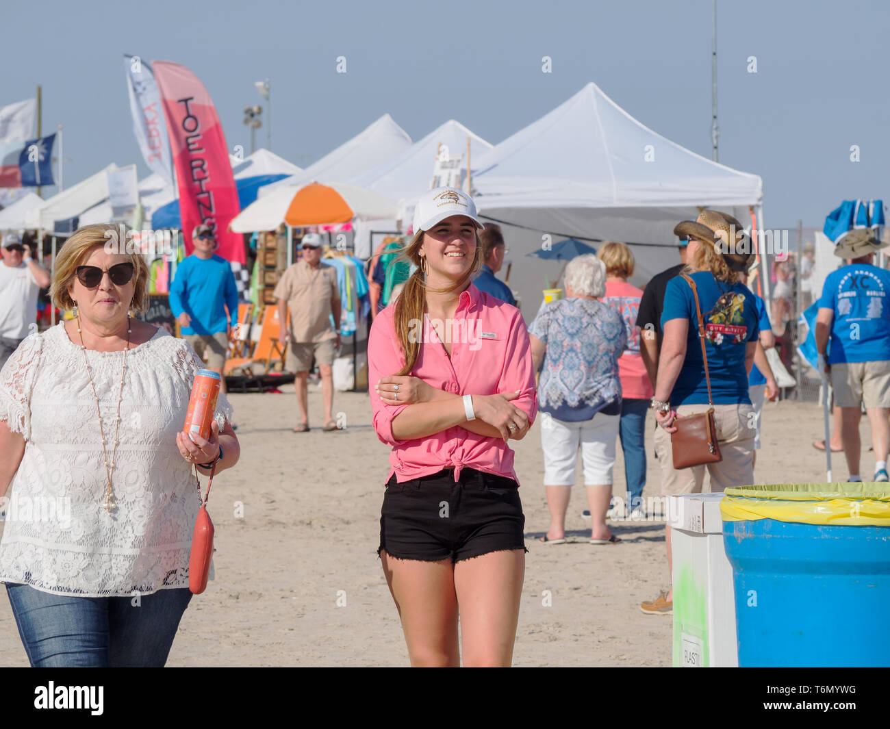 Une jeune femme portant un chandail rose, short noir et blanc une casquette se distingue parmi les visiteurs du Texas 2019 Sandfest à Port Aransas, Texas USA. Banque D'Images