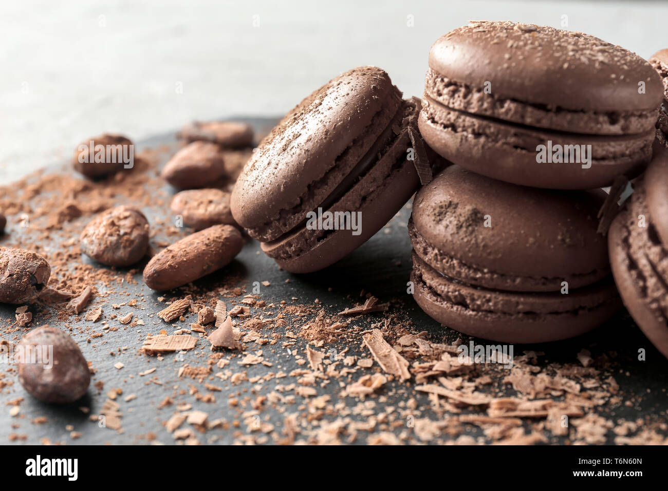 Plaque en ardoise avec de délicieux macarons au chocolat et cacao en fèves, gros plan Banque D'Images